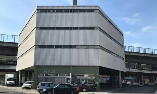 Modernes Gebäude neben Autobahnbrücke bei Sonnenschein.